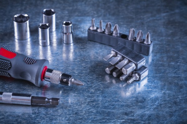 Toolset of screwdriver with stainless replaceable bits and torx on scratched metallic background