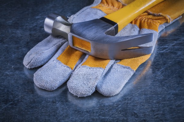 Safety gloves with claw hammer on scratched metallic background construction concept