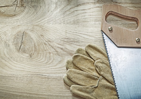 Safety gloves hacksaw on wooden board construction concept
