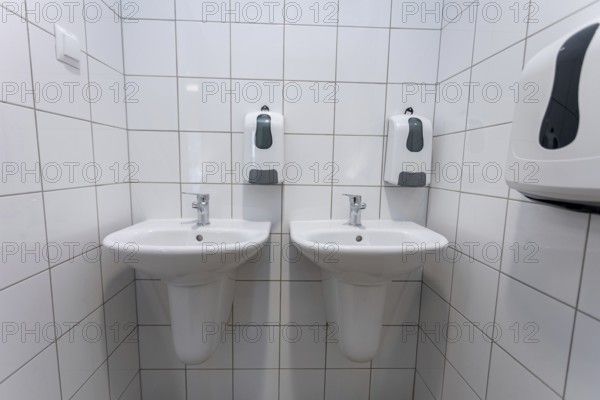 A clean and contemporary public restroom that features two modern washbasins along with convenient