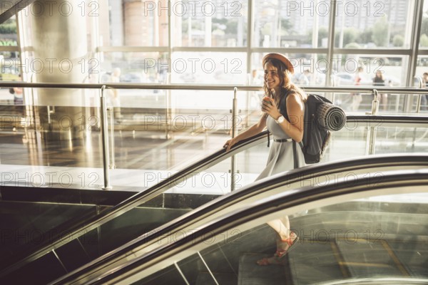 Portrait Smiling Woman Wearing Hat In Airport At Escalator. people travelling with hand luggage.