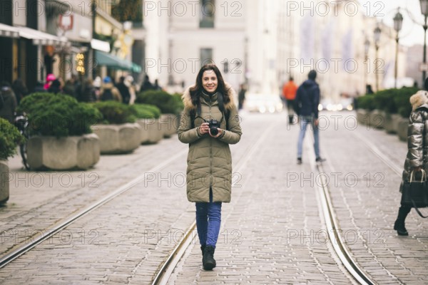 Beautiful young woman tourist with long hair stands on the background of the central street in the