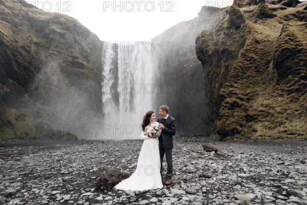 Wedding couple near Skogafoss waterfall. Destination Iceland wedding. The groom hugs the bride by