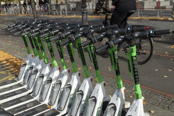 Traffic, mobility, cyclists and lined-up e-scooters from Lime in autumn on a street in Berlin,