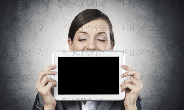 Businesswoman holding tablet computer with blank screen. Beautiful woman with closed eyes showing