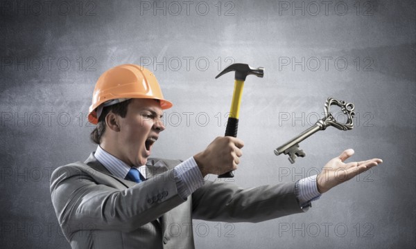 Furious businessman going to crash with hammer steel key. Young handsome contractor in business