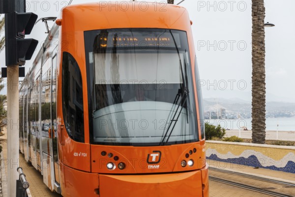 Alicante, Spain, October 14, 2023: Orange streetcar running along the promenade between Alicante