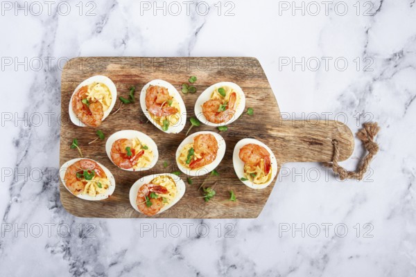 Boiled eggs stuffed with yolk and seasoned with mayonnaise, stuffed eggs with shrimp, on a wooden