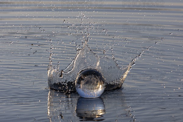 A glass sphere creates water droplets with a dynamic water crown, Mindelheim, Allgäu, Bavaria,