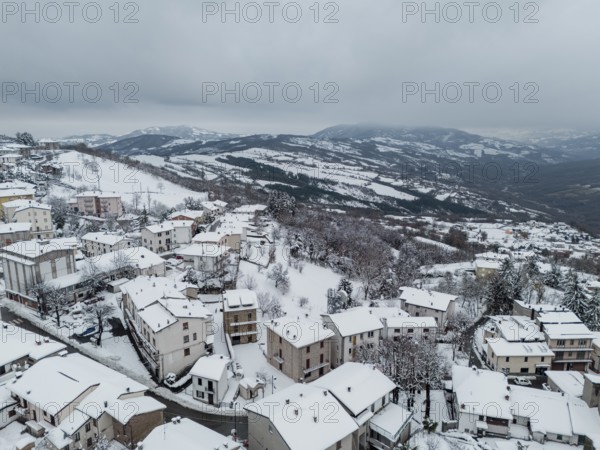 Aerial view of snow-covered houses and trees in bore, a small village nestled in the hills