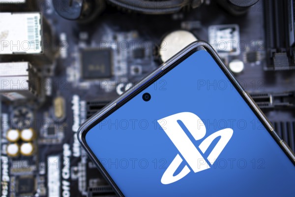 Person holding cellphone with logo of video gaming platform PlayStation Network (PSN) in front of
