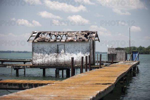 A weathered dock and shed sit along on the Detroit River along the shoreline of Southwestern