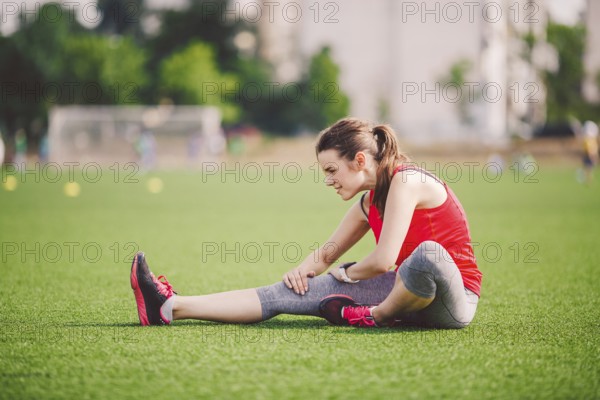 Theme sport and health. Young beautiful Caucasian woman sitting doing warm-up, warming up muscles,