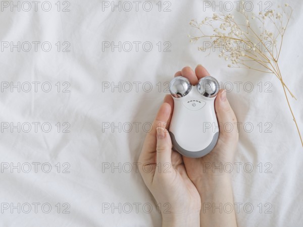 Microcurrent concept. Face massager with micro currents for home use and skincare on white bed.