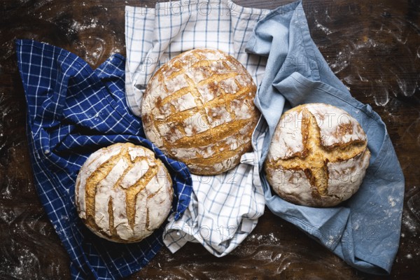 Above view with three homemade sourdough loaves of bread on towels. Freshly baked and delicious