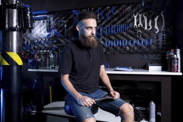 Portrait of small business owner of young man with beard. Guy bicycle mechanic workshop worker