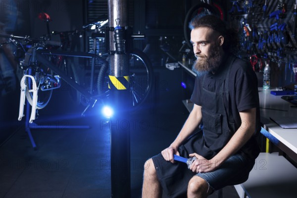 Portrait of small business owner of young man with beard. Guy bicycle mechanic workshop worker