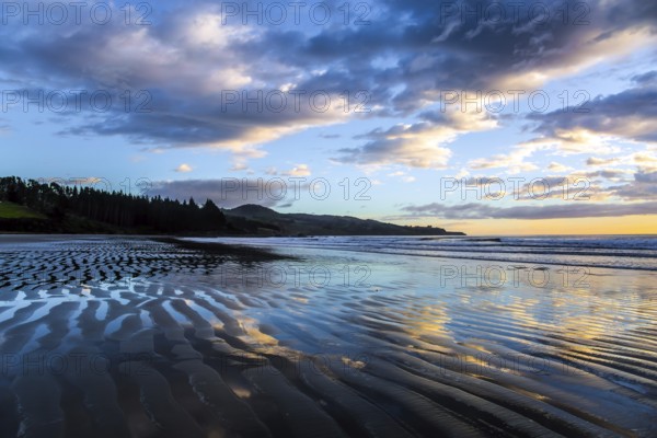 Strips of sand and water left by the ocean tide. Sunrise over the ocean. New Zealand, Pacific Coast