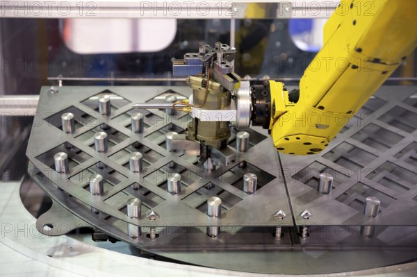 Yellow robotic arm arranges metal elements after being produced. Automatic industrial machinery