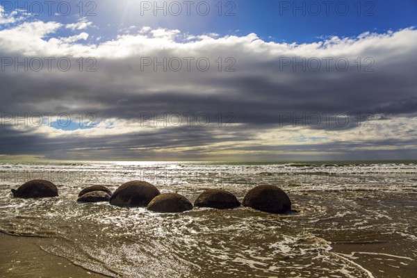 Moeraki boulders. Ocean tide begins. Group of large round boulders on the coast of the South Island