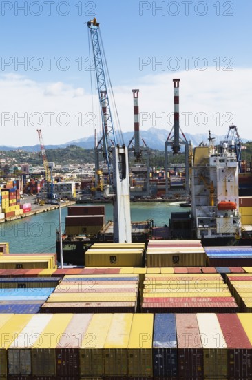 High angle view of stacked rectangular metal box shipping containers and gantry cranes on dock in
