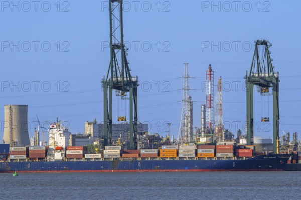 Gantry cranes and stacked containers on container ship docked at container terminal in the port of