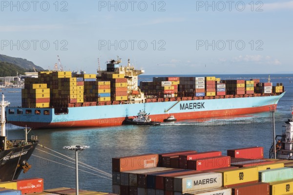 Maersk Serangoon cargo ship loaded with metal box shipping containers being guided by pilot boats