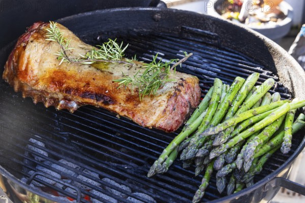 Barbecue with Easter roast. Rack of lamb and green asparagus grilled on an outdoor kettle barbecue.