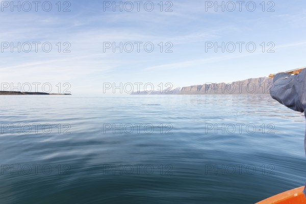 Greenlandic man hunting for seal in Greenland, pointing the gun towards the water, Greenland, North