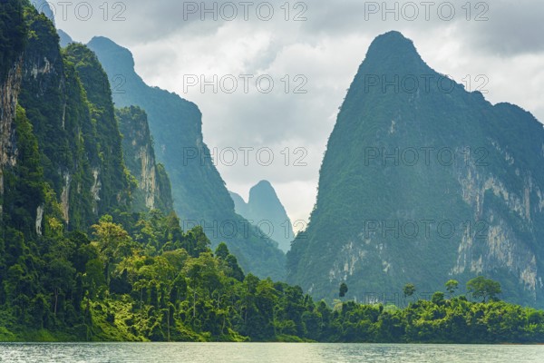 Misty mountain peaks covered in dense greenery under a cloudy sky, Cheow Lan Lake, Khao Sok