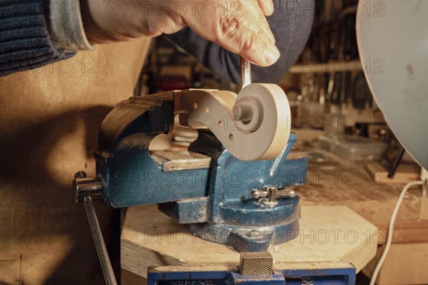 Italian luthier is meticulously shaping the scroll of a violin using a gouge, with the piece