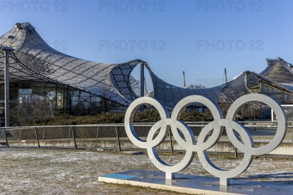 Sculptures of the Olympic rings and in the background the Olympic site with the Olympic buildings