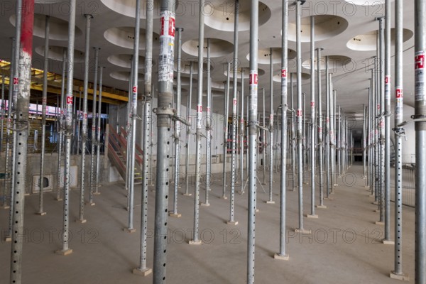 Rows of scaffolding in an unfinished interior with perforated ceiling, supports, construction site