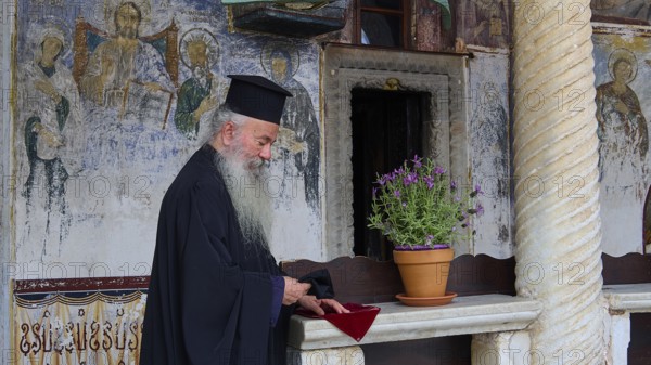 Priest with traditional robe in an interior with mural painting, Monastery of St John the