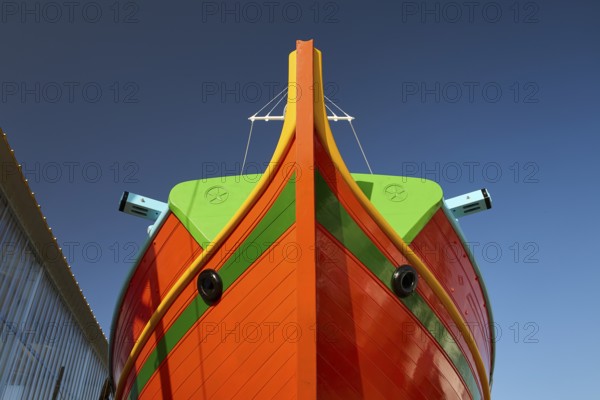 Close-up of the bow of a large orange boat in front of a clear sky, Diakofti boatyard, new