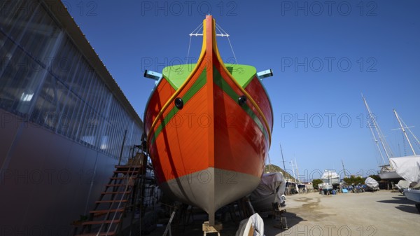 Large orange boat in a shipyard in front of a blue sky, boatyard Diakofti, new construction of a