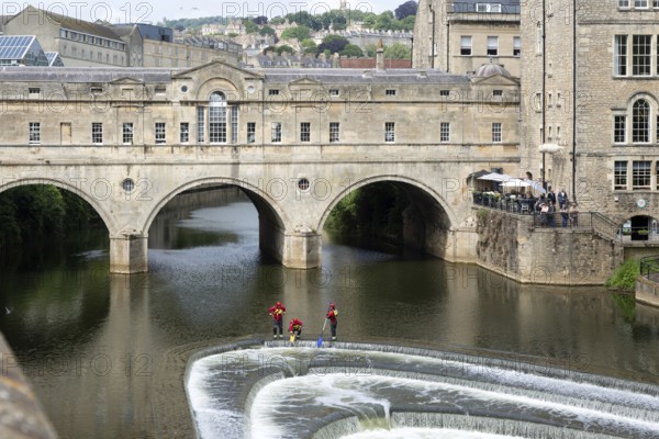 Avon Fire and Rescue Service personnel on weir on River Avon, Pulteney Bridge, city of Bath, north