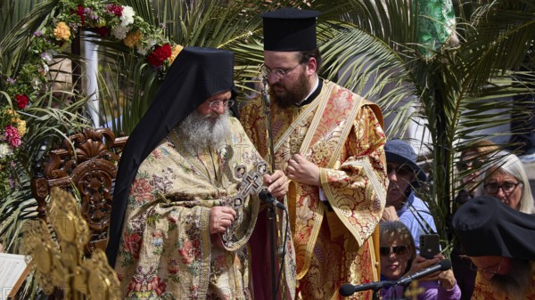 Two priests in rich robes stand in the middle of a solemn ceremony with religious symbols and