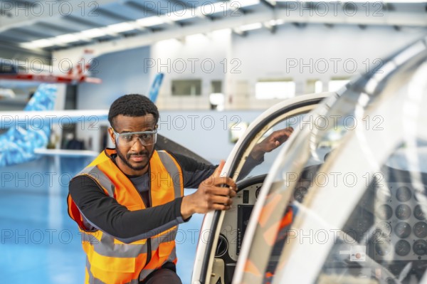 Aircraft maintenance engineer wearing safety glasses and a high visibility vest, performing a pre