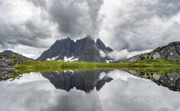 Small lake in mountain landscape, hike to Mount Barden, reflection with mountain peak Breidtind,