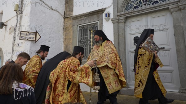 Priests in gold and black robes enter a door during a procession, Orthodox ceremony, monks of St