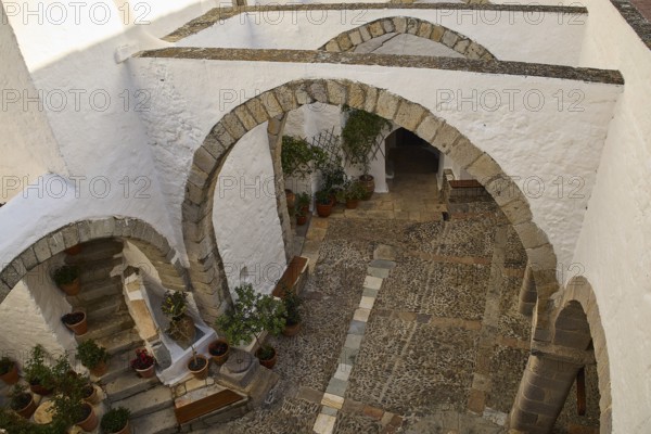 White courtyard with stone arches and plants in traditional style, Monastery of St John the