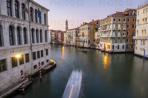 View of the Grand Canal with gondoliers at sunset, picturesque evening mood with illuminated