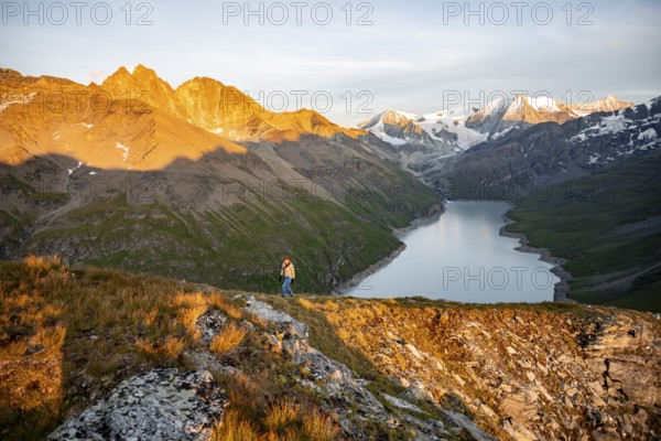 Mountaineer on the summit of Mont de la Blana, alpenglow at sunset, view of a blue mountain lake,