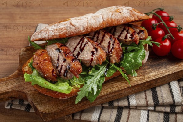 Sandwich with duck breast and arugula, balsamic sauce, on a wooden chopping board, breakfast,
