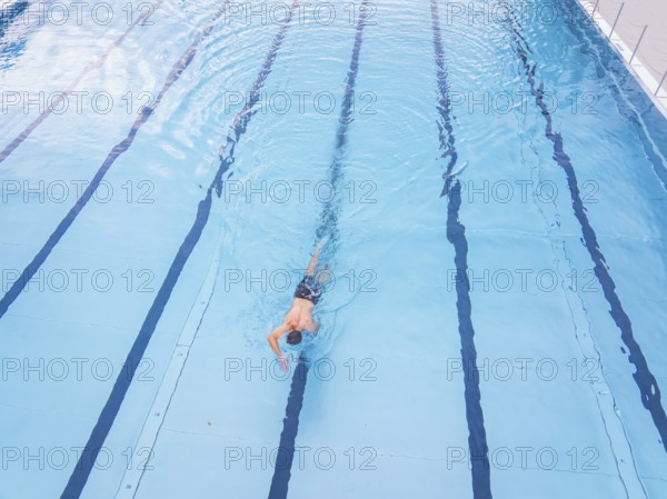 A person swims along the lanes in a large, blue swimming pool, outdoor pool Calw, Black Forest,