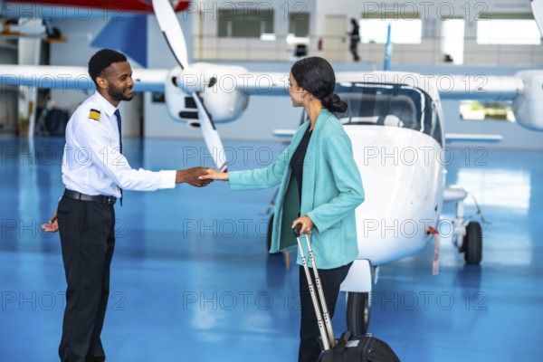 Pilot and businesswoman shaking hands in front of a private jet inside a hangar, finalizing their