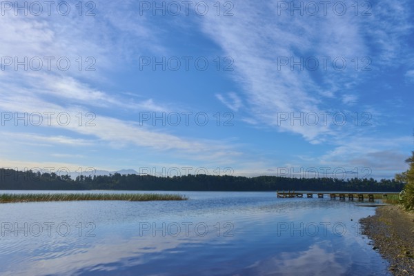 A long jetty on the shore of a calm lake under an overcast sky, Lake Mahinapua, Ruatapu, South