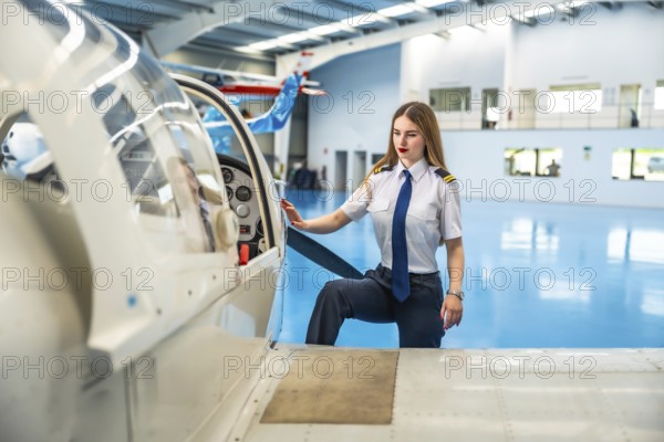 Confident female pilot boarding a small aircraft in a hangar, readying for an exciting flight and