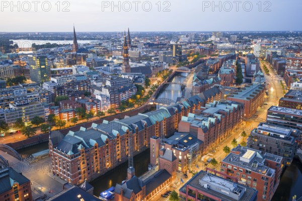 Aerial view of the Speicherstadt Hamburg at blue hour with churches and Alster in the background,